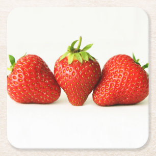 Drie aardbeien op witte coaster kartonnen onderzetters