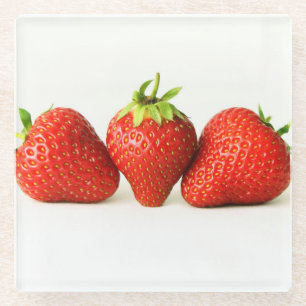 Drie aardbeien op witte kuit glazen onderzetter