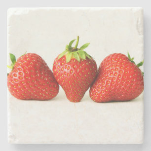 Drie aardbeien op witte kust stenen onderzetter