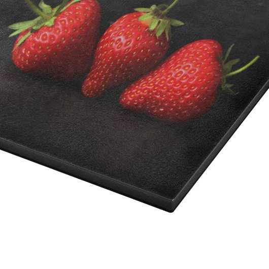 Drie aardbeien op zwart cbcna snijplank (Hoek)