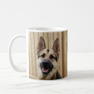 Duitse herder zit bij houten hek koffiemok