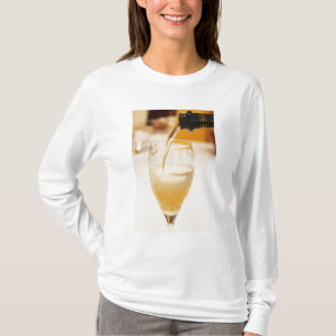 Een champagneglasfluit die wordt gevuld met Gosset T-shirt