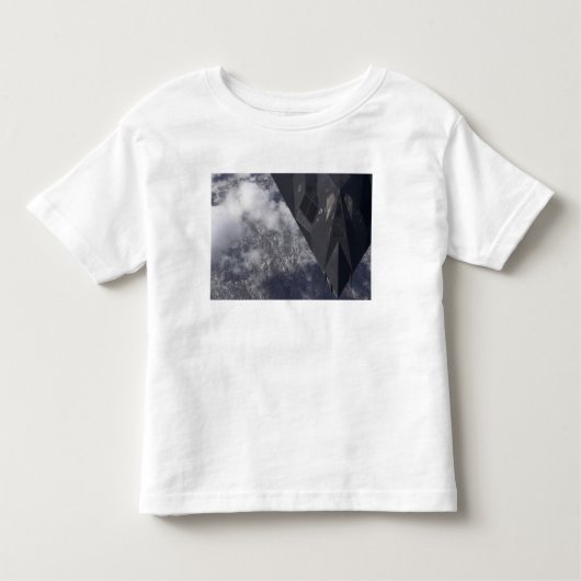 Een F-117A Nighthawk vliegt hoog boven de bergen Kinder Shirts (Voorkant)