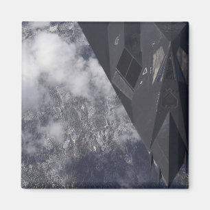 Een F-117A Nighthawk vliegt hoog boven de bergen Magneet