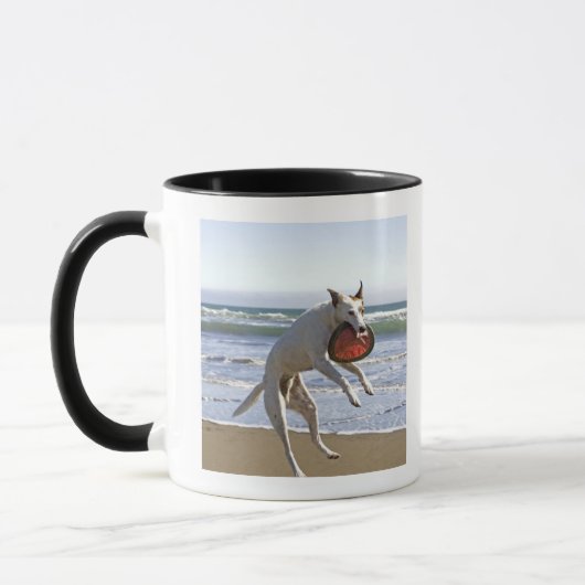 Een hond springt naar een frisbee op het strand mok (Links)