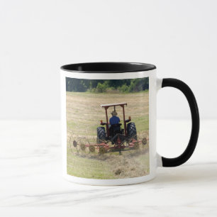Een jonge jongen bestuurt een tractor die oogst mok