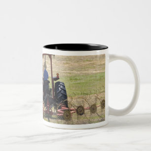 Een jonge jongen die een trekker bestuurt die oogs tweekleurige koffiemok