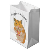 Een kleine kersthamster met een cadeau medium cadeauzakje (Voorkant Gekanteld)