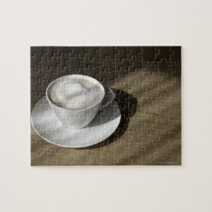 Een kop cappuccino-koffie ligt op een eikel legpuzzel