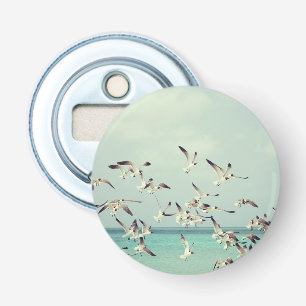 Een kudde vliegende meeuwen boven de oceaan. button flesopener