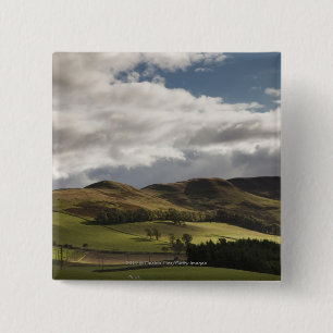 Een landschap met rolheuvels en wolken boven het h vierkante button 5,1 cm