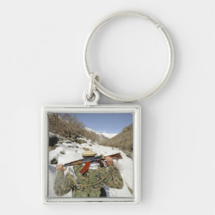 Een Mujahadeen Guard loopt met een Amerikaans mili Sleutelhanger