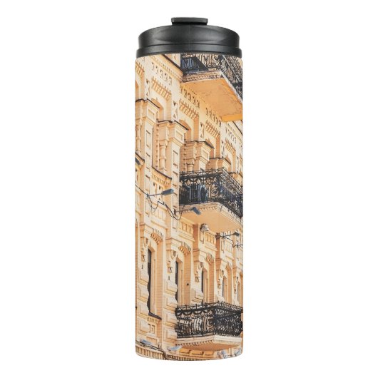 Een oud geel huis met ijzerbalkons. f. thermosbeker (Voorkant)