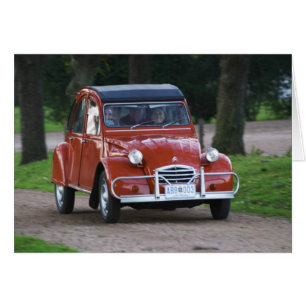 Een oude rode 2CV-wagen met een lachende vrouw