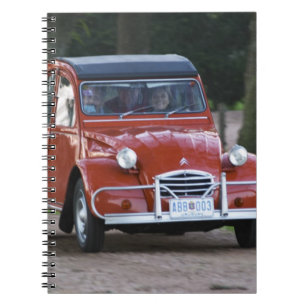 Een oude rode Citroen 2CV auto met een lachende vr Notitieboek