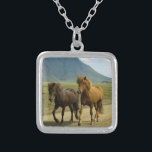 Een paar bruine IJslandse pony's Zilver Vergulden Ketting<br><div class="desc">Een heel schattige en schattige foto-opname van twee ijslandse pony's die een modderweg aftrokken. De ene is een baai en de andere is kastanjekleurig. Hun prachtige mannetjes blazen in de wind. Een prachtig berglandschap kan op de achtergrond worden gezien en geeft een gevoel van verwondering aan dit afbeelding. Vrouw aan...</div>