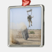 Een pararescueman valt het gebied binnen metalen ornament (Links)