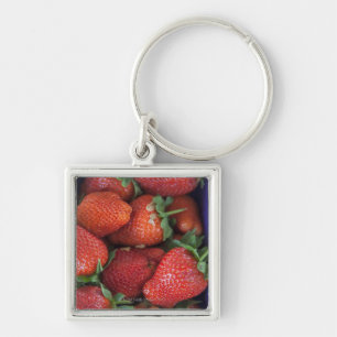 een punnet van rijpe verse aardbeien die te koop w sleutelhanger