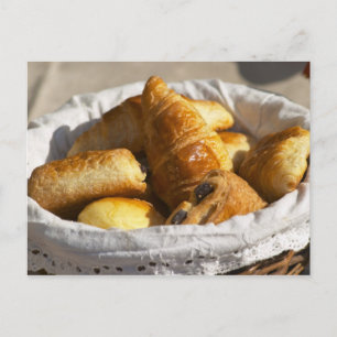Een rieten ontbijtmand met croissants, en briefkaart