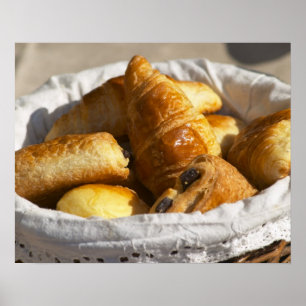 Een rieten ontbijtmand met croissants, en poster