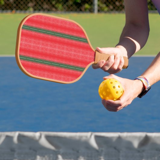 Een rood en groen gestreepte achtergrond pickleball paddle (Insitu)