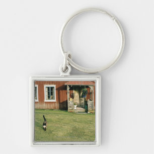Een rood huis met een kat op het gazon. sleutelhanger