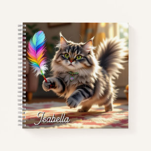 Een Schattigee donzige kat die een veer achterna z Notitieboek