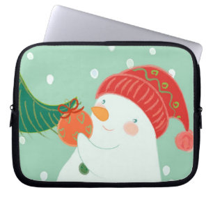 Een sneeuwman die een versiering aan een boom hang laptop sleeve
