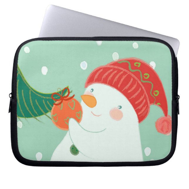 Een sneeuwman die een versiering aan een boom hang laptop sleeve (Voorkant)