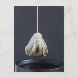 Een theezakje zit in een beker. briefkaart