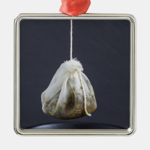 Een theezakje zit in een beker. metalen ornament