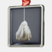 Een theezakje zit in een beker. metalen ornament (Links)