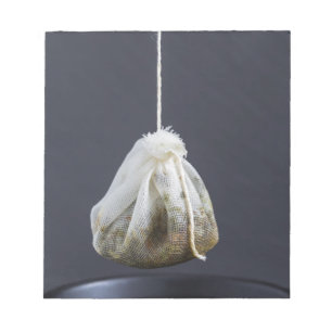 Een theezakje zit in een beker. notitieblok