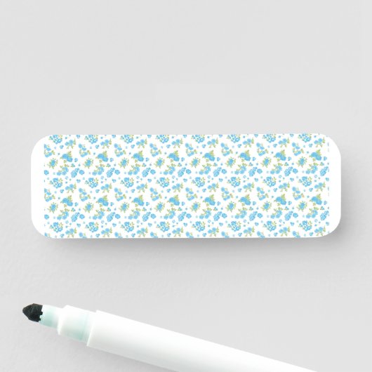 Een witte achtergrond met blauwe bloemen en groene naamplaatje (In situ)