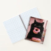 Een zwarte kat houdt roze donuts in zijn poten notitieboek (Binnen)