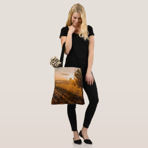 Eenzame boom op het broeiveld in de gouden zonsopg tote bag
