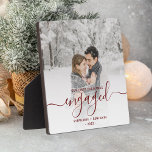 Eerste kerstcadeautje Foto Burgundy Red Script Fotoplaat<br><div class="desc">Herdenking je verloving met deze mooie moderne keepaardplak. In de tekst met de boekrode tekst staat: "Onze eerste kerst bezet", met het woord "betrokken" in elegant handschrift met een bloei voor en na. Vervang het afbeelding van de steekproef met uw favoriete foto, en voeg uw namen en het jaar toe....</div>