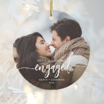 Eerste Kerstmis Aangepaste foto White Script Keramisch Ornament<br><div class="desc">Herinneer je verloving met dit mooie, moderne keepdoesie ornament. In de witte tekst staat "Onze eerste kerst bezet" met het woord "betrokken" in elegant kalligrafiescript met decoratieve swashes voor en na. Vervang het afbeelding van de steekproef met uw favoriete foto, en voeg uw namen en het jaar toe. Een zwarte...</div>