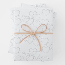 Elegante decoratieve zilveren hartjes aan een witt inpakpapier vel