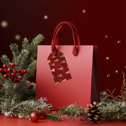 Feestelijke gouden kerstbomen op rood cadeaulabel