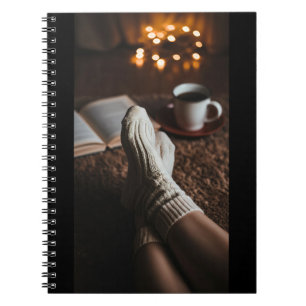 Feminine feet wrapped in soft, fluffy socks, with notitieboek