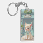 Fluffy kitten met blauwe boog bij banketbakkerij sleutelhanger (Voorkant Links)