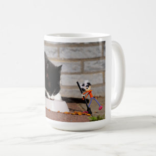 Fubby schoonmaken met de bezem bij etende Kat. Koffiemok