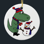 Funny T-Rex Dinosaur Building Snowman Keramisch Ornament<br><div class="desc">Geweldige groene t-rex dinosaurus die een sneeuwman originele kunst bouwt. Hij draagt een blauw en rood gebreid pet en sjaal en rode wanten en laarzen.  Kan douanetekst ook toevoegen wanneer het opdracht geven tot van.</div>