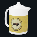 Galloping Bison Theepot<br><div class="desc">Op de huidzijde van een bever-pelt die op een moerashoepel is uitgerekt, wordt een galoppingbizon geschilderd. De bizon (Bison bison), het grootste landzoogdier in Noord-Amerika, wordt beschouwd als een sleutelsoort: ze roamden ooit het continent in grote kuddes, en hun graasdruk hielp bij het vormgeven van de ecologie van de Grote...</div>