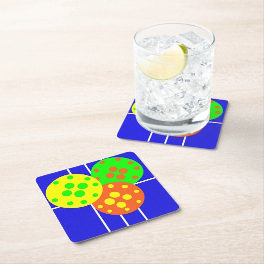 Geel, sinaasappel, & groene pickleballs op blauw h kartonnen onderzetters (Insitu)