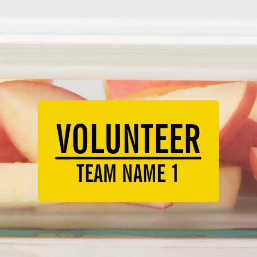 Gele vrijwilligersbadge met de naam van het team v labels (Aangebracht)