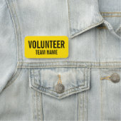 Gele vrijwilligersbadge met de naam van het team v naamplaatje (In situ)