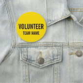 Gele vrijwilligersbadge met de naam van het team v naamplaatje (In situ)