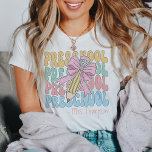 Gepersonaliseerd met naam Preschool Teacher Custom T-shirt<br><div class="desc">Vier het begin van een nieuw schooljaar met ons gepersonaliseerde With Name Preschool Teacher Custom Crewneck T-Shirt, de perfecte mix van comfort, stijl en personalisatie. Dit charmante t-shirt is ontworpen met de toegewijde kleuterjuf in gedachten, met een heerlijke roze strik en retro-geïnspireerde graphics die een vleugje coquette flair toevoegen. Pas...</div>
